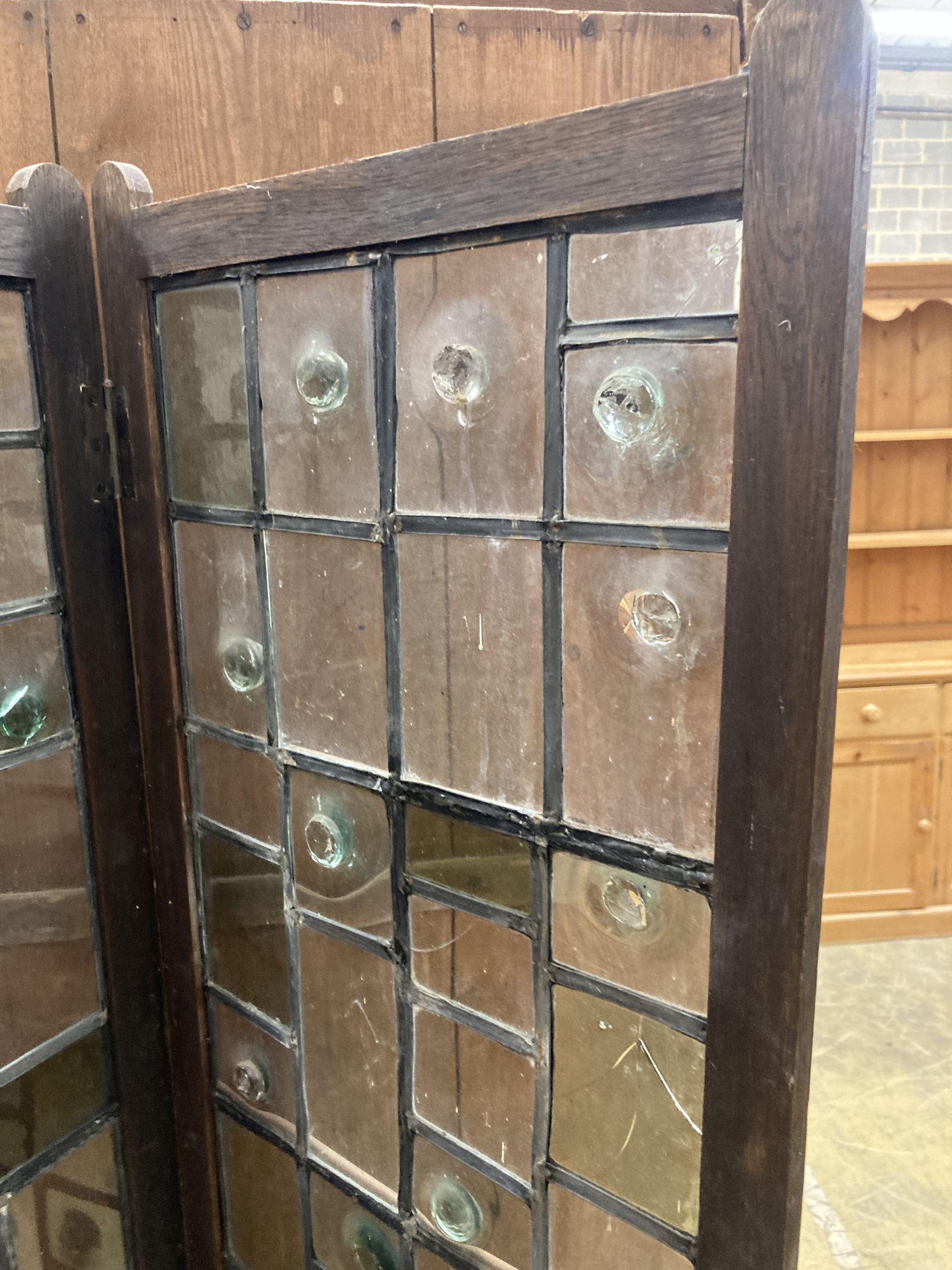 An early 20th century glazed oak two fold screen, each panel width 51cm, height 176cm